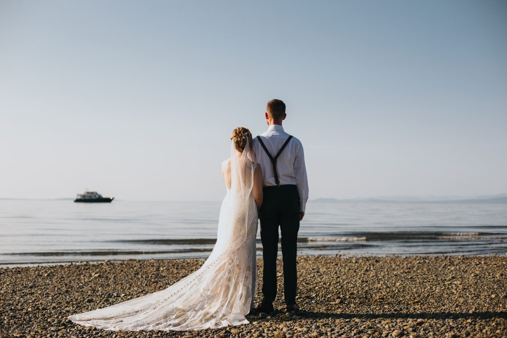 wedding couple standing staring out at the ocean