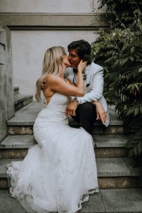 bride and groom sitting on the stairs kissing
