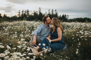 pregnant couple kissing in a daisy field
