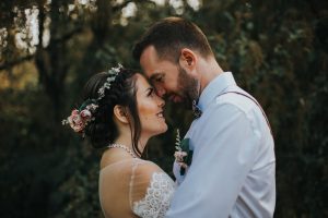 couple hugging with their foreheads touching in the forest