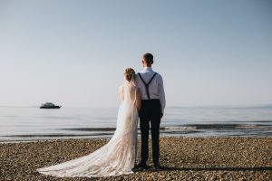 wedding couple standing staring out at the ocean