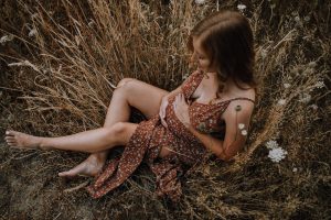 pregnant woman sitting in wildflowers and tall grass