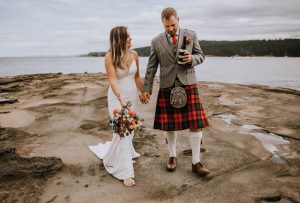 bride and groom walking along the water