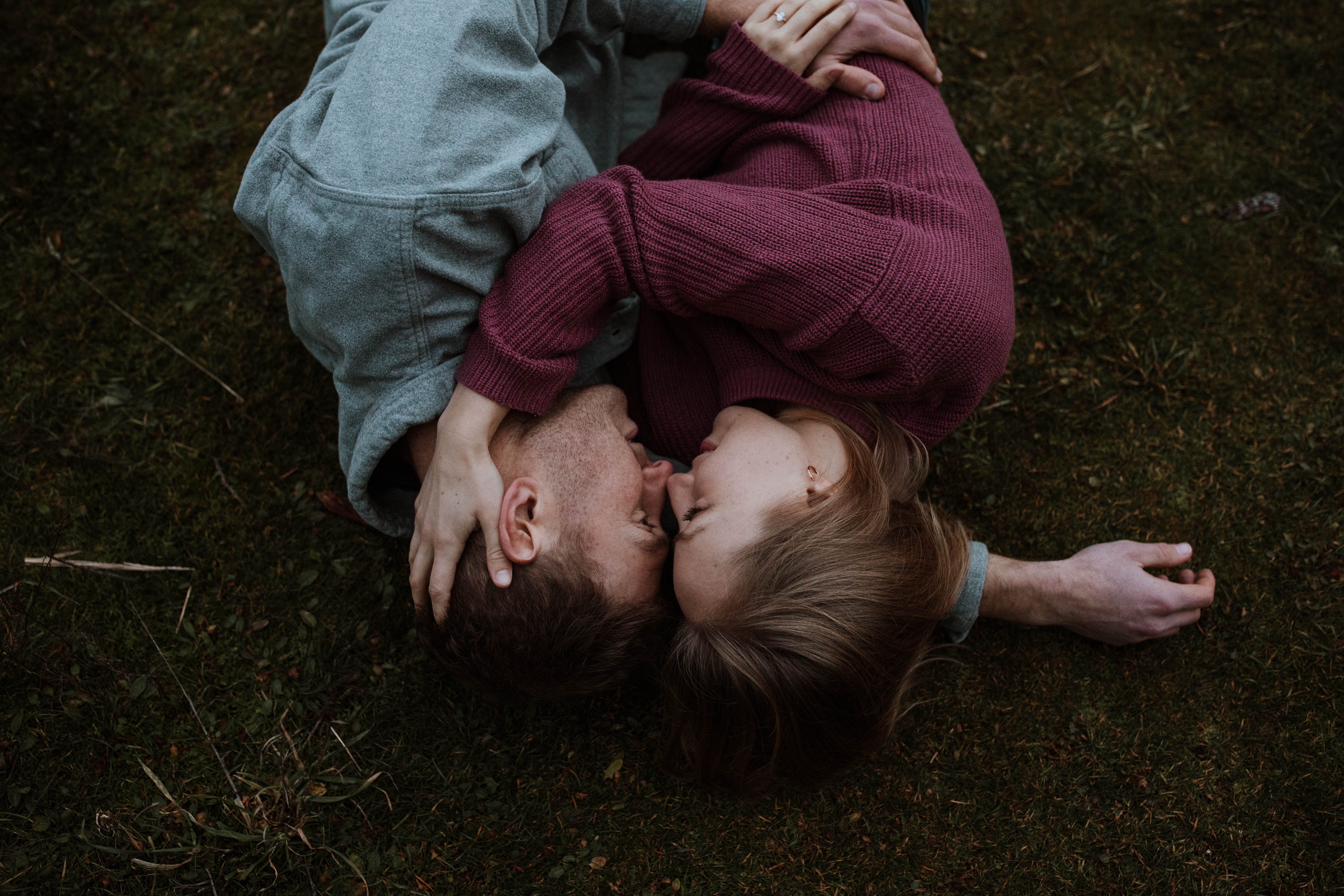 couple snuggling and laying on grass together